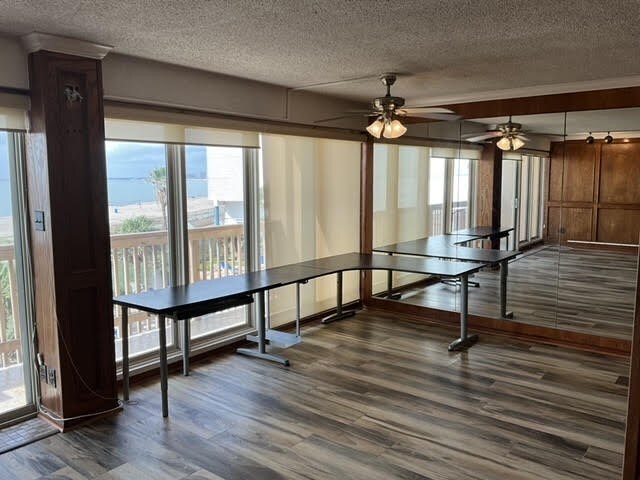 unfurnished dining area featuring ceiling fan, a textured ceiling, and dark hardwood / wood-style floors