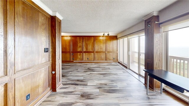 corridor featuring wood walls, a textured ceiling, and light hardwood / wood-style flooring