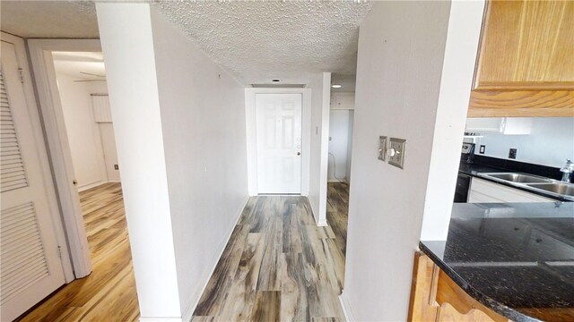 corridor featuring hardwood / wood-style floors, a textured ceiling, and sink