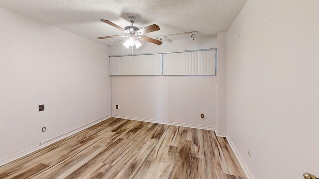 spare room featuring light wood-type flooring, a textured ceiling, and ceiling fan