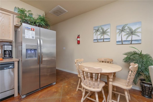 kitchen with light brown cabinetry, stainless steel appliances, and tile patterned flooring