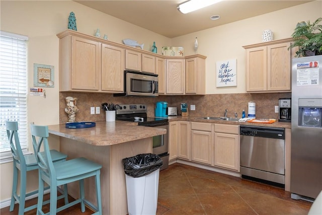 kitchen featuring a breakfast bar, backsplash, sink, appliances with stainless steel finishes, and kitchen peninsula