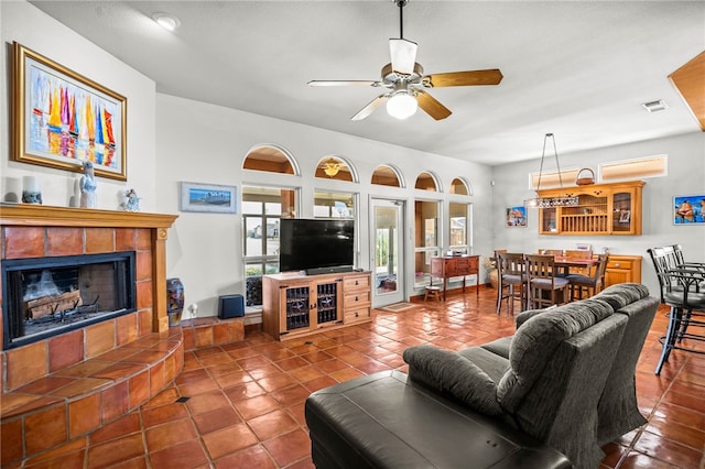 living room with tile patterned flooring, a tiled fireplace, and ceiling fan