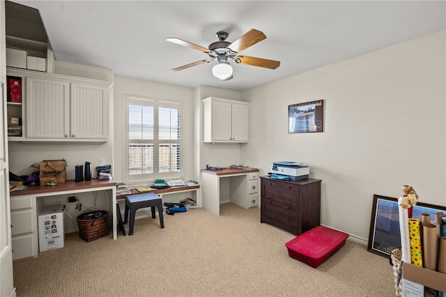 office area with built in desk, ceiling fan, and light carpet