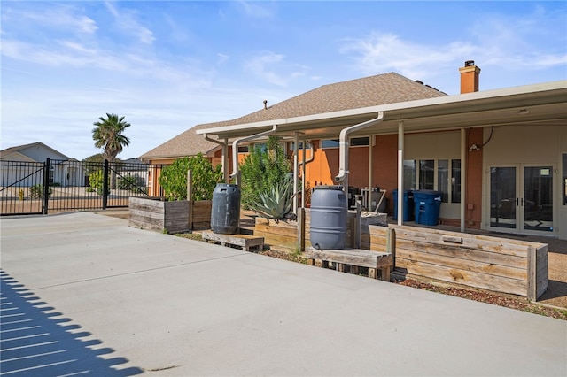 15746 Cuttysark St, Corpus Christi, TX 78418 - view of front facade featuring french doors, a chimney, a patio area, and roof with shingles