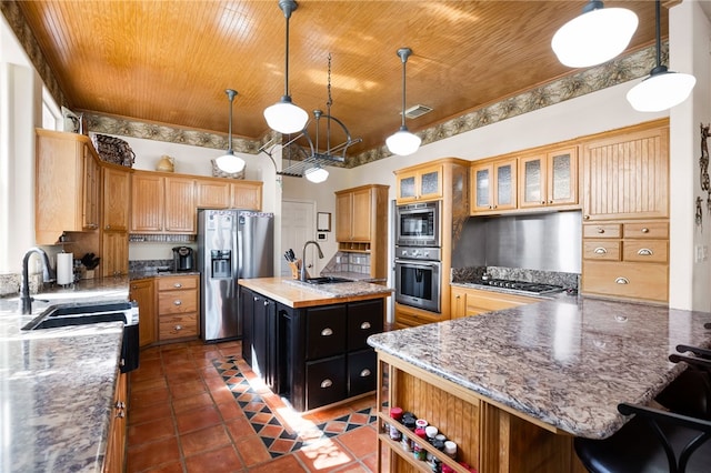 kitchen featuring stainless steel appliances, decorative light fixtures, a kitchen bar, sink, and a kitchen island with sink