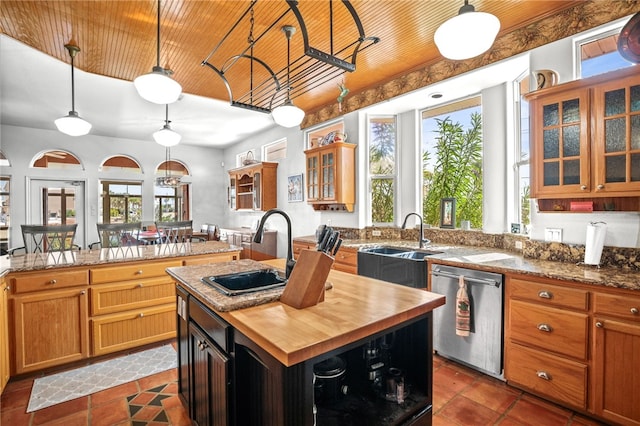 kitchen featuring a kitchen island, wooden counters, pendant lighting, sink, and stainless steel dishwasher