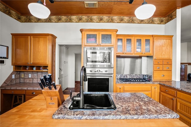 kitchen featuring sink, appliances with stainless steel finishes, dark stone countertops, decorative light fixtures, and wood ceiling