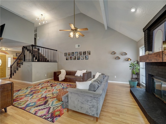 living room with a brick fireplace, light wood-type flooring, a textured ceiling, and high vaulted ceiling