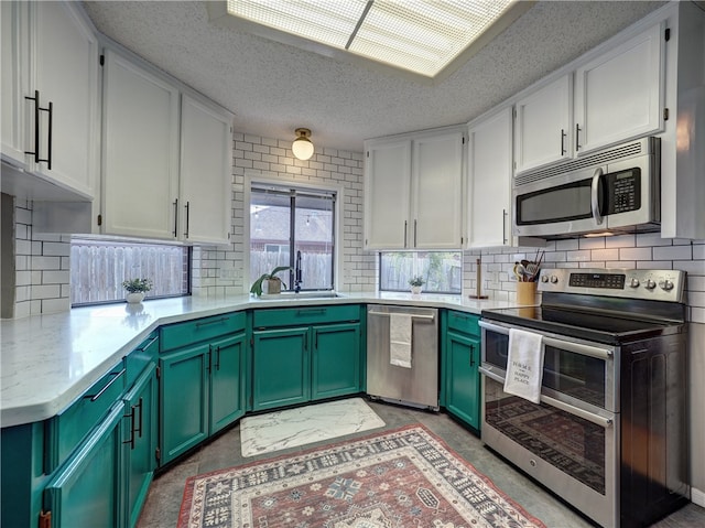 kitchen featuring stainless steel appliances, green cabinets, white cabinetry, tasteful backsplash, and a textured ceiling