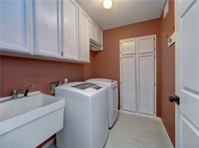 laundry area featuring a textured ceiling, separate washer and dryer, cabinets, and sink