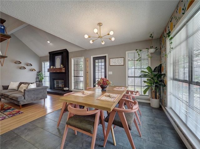 dining area featuring a fireplace, a textured ceiling, a notable chandelier, dark hardwood / wood-style floors, and lofted ceiling