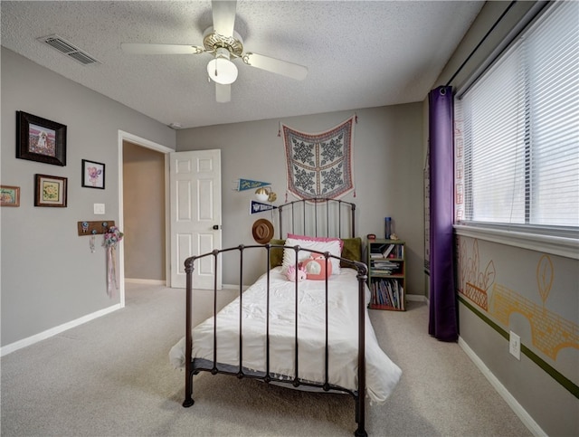 bedroom with a textured ceiling, carpet floors, and ceiling fan