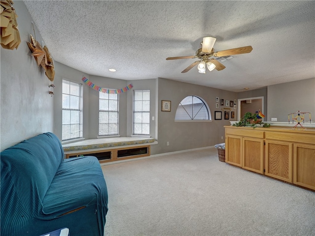 living room featuring a textured ceiling, light colored carpet, and ceiling fan