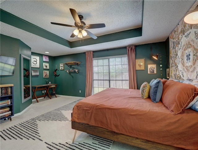 bedroom with a tray ceiling, a textured ceiling, ceiling fan, and carpet floors