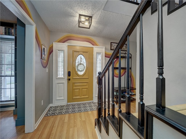 foyer entrance featuring light hardwood / wood-style flooring and a textured ceiling