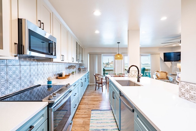 kitchen featuring sink, stainless steel appliances, tasteful backsplash, pendant lighting, and white cabinets