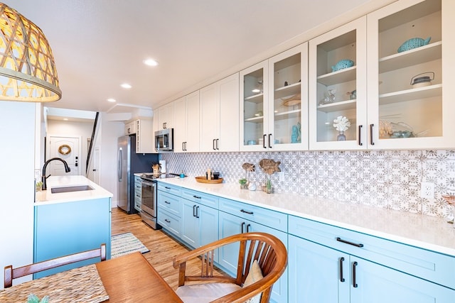 kitchen featuring decorative backsplash, appliances with stainless steel finishes, sink, pendant lighting, and white cabinetry