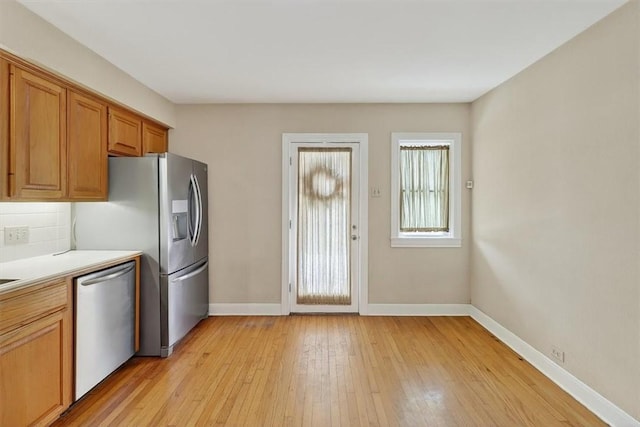 521 Del Mar Blvd, Corpus Christi, TX 78404 - kitchen with stainless steel appliances, light countertops, light wood-style flooring, brown cabinets, and decorative backsplash