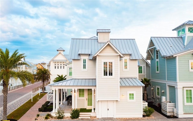 rear view of house with metal roof, a residential view, a porch, and a standing seam roof