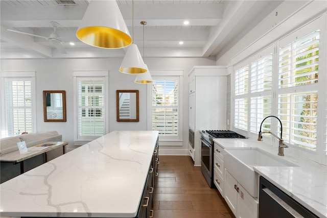 kitchen featuring a kitchen island, beamed ceiling, gas range, dishwasher, and a sink