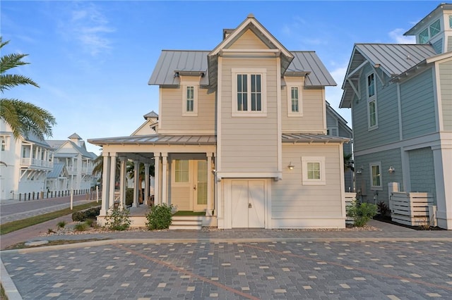 view of front of home featuring covered porch, metal roof, a standing seam roof, and uncovered parking