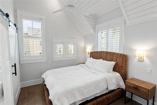 bedroom with a barn door, multiple windows, and dark wood-type flooring