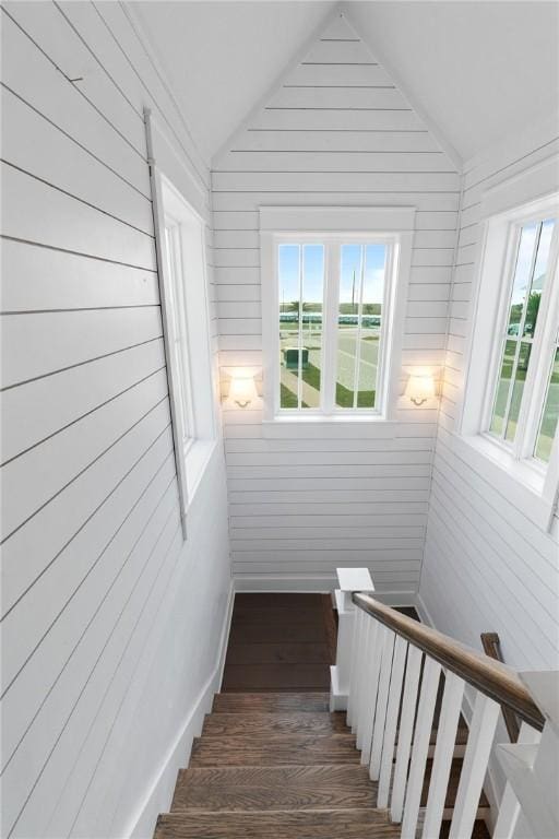 staircase featuring baseboards, wood finished floors, and vaulted ceiling