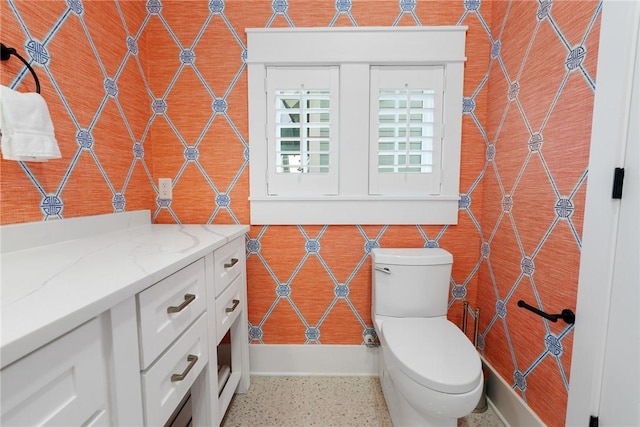 bathroom with speckled floor, toilet, tile walls, and vanity