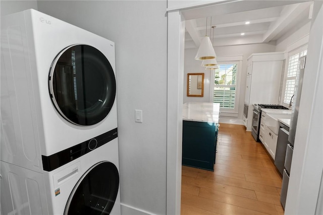 clothes washing area with laundry area, recessed lighting, stacked washing maching and dryer, and light wood-style floors