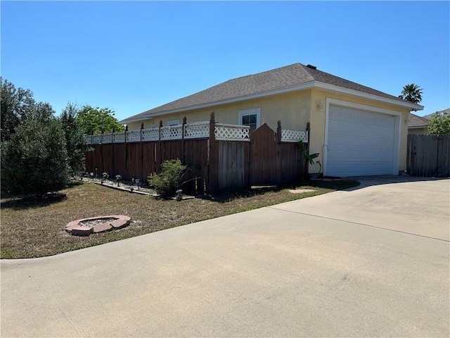 13838 Sea Horse Ave, Corpus Christi, TX 78418 - view of side of property with concrete driveway, a garage, an outdoor fire pit, and stucco siding