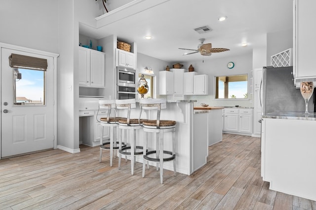 kitchen with visible vents, white cabinets, a center island, stainless steel appliances, and light countertops