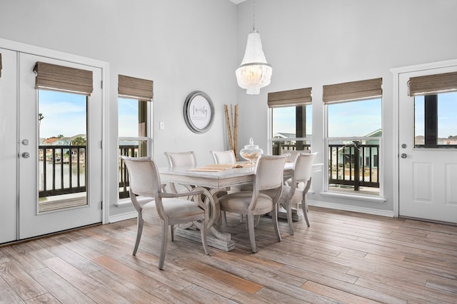 dining room with light wood-style flooring, a high ceiling, and a wealth of natural light