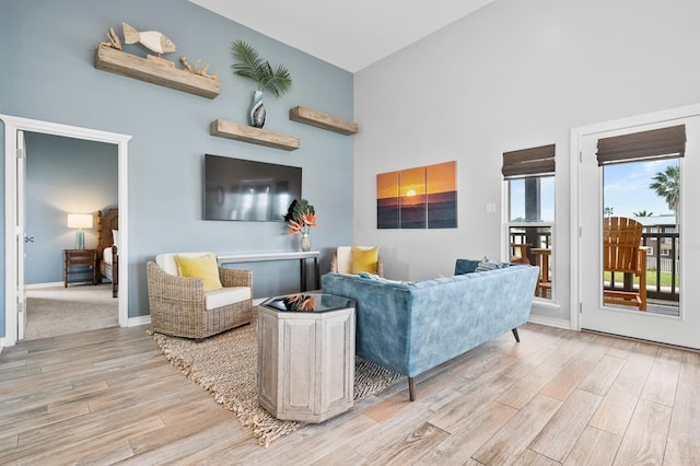 living area featuring baseboards, a high ceiling, and light wood-style floors