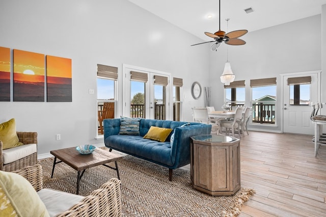 living area featuring a healthy amount of sunlight, light wood-style flooring, a ceiling fan, and french doors