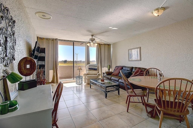 living room with ceiling fan and a wall of windows