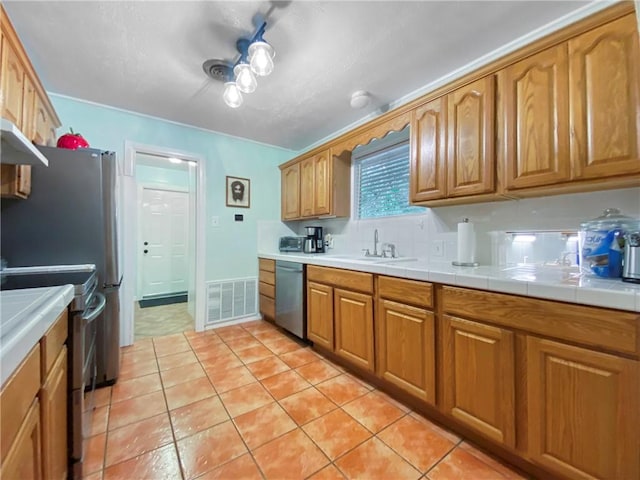 kitchen featuring appliances with stainless steel finishes, tile countertops, light tile patterned floors, and sink