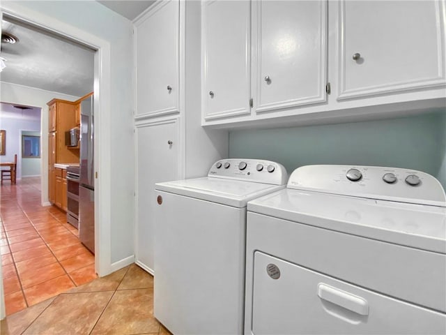 clothes washing area featuring separate washer and dryer, cabinets, and light tile patterned floors