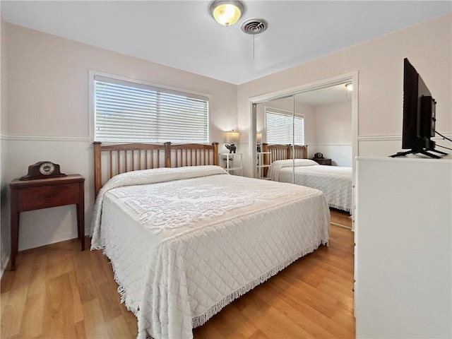 bedroom featuring a closet, wood-type flooring, and multiple windows