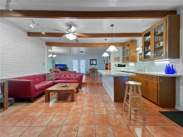 kitchen featuring pendant lighting, track lighting, a breakfast bar, beam ceiling, and ceiling fan with notable chandelier