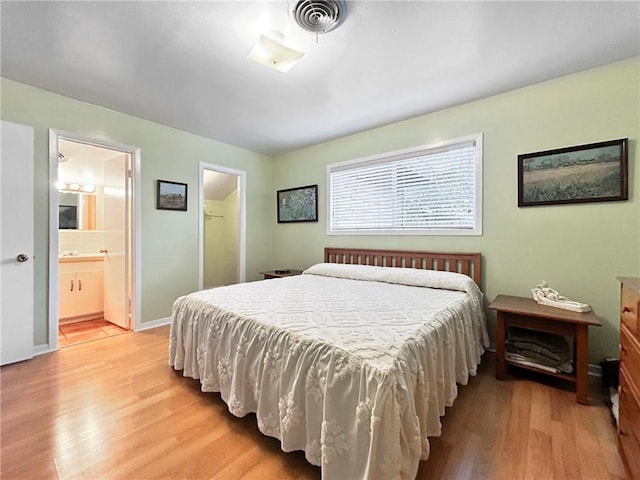 bedroom featuring light wood-type flooring, connected bathroom, and a closet