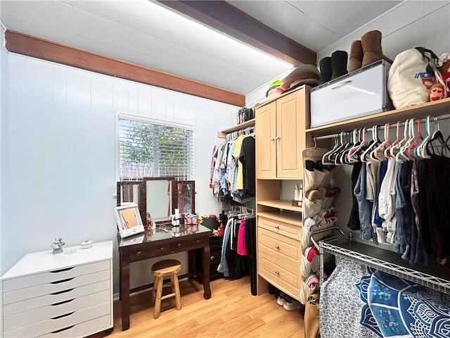 walk in closet with beam ceiling and light hardwood / wood-style flooring