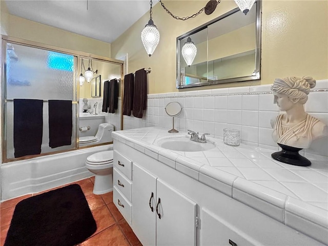 full bathroom featuring toilet, tile walls, bath / shower combo with glass door, tile patterned floors, and vanity