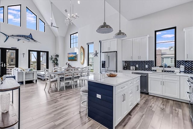 kitchen with an inviting chandelier, light wood-type flooring, a center island, stainless steel appliances, and open floor plan