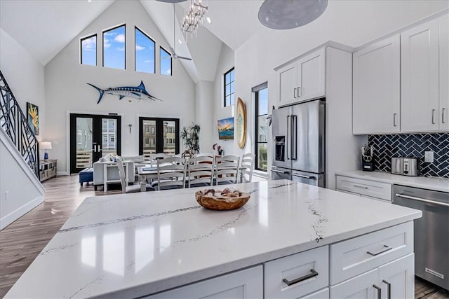 kitchen featuring backsplash, appliances with stainless steel finishes, plenty of natural light, and light wood finished floors