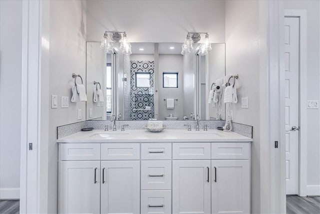 full bathroom with wood finished floors, double vanity, and a sink