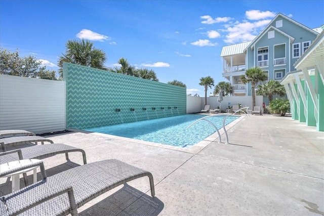 pool with a patio area and fence