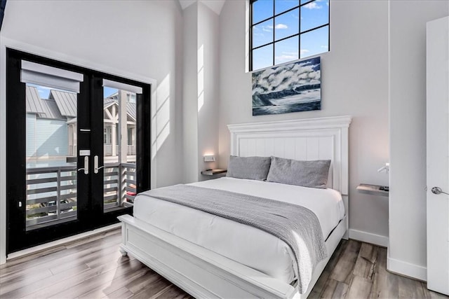 bedroom with french doors, access to exterior, wood finished floors, and baseboards