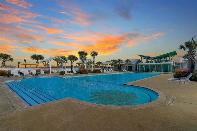 pool at dusk with a patio and a community pool