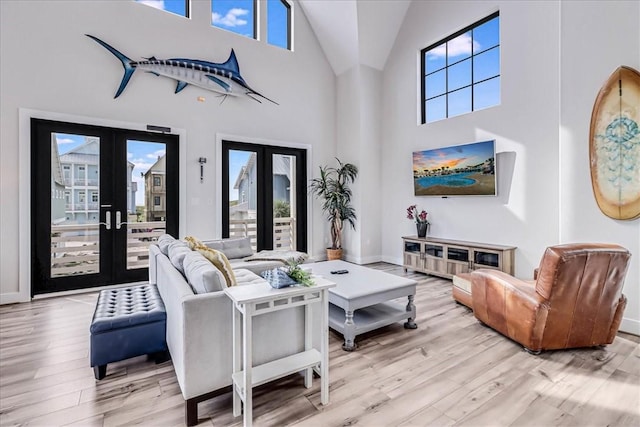 living room featuring light wood-type flooring, french doors, high vaulted ceiling, and baseboards